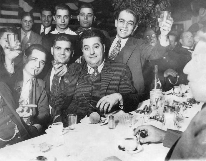 Fotogrāfija publicēta 1930. gada 27. novembrī ar parakstu: ““Labā griba”. Un šeit starp gangsteriem ir miers. Tas ir tosts par godu Ričardam Boiardo (vidū), kurš sarīkojis sev svinības sakarā ar divu dienu pamieru ar Abi Zvilmanu, Ņūarkas trešā rajona bandītu bosu.” Par “Zābaku” (“Richie the Boot”) Boiardo iesaukts tādēļ, ka viņa kriminālā karjera 1920. gados sākās ar nelegālo alkohola tirgošanu; cilvēku, kas ar to nodarbojās, amerikāņi slengā sauca par “bootlegger” – no vārda “bootleg”, zābakstulms: kontrabandisti darbojās tik veikli, it kā pārnēsātu alkoholu zābaku stulmos. Ap 1930. gadu Ričijs Zābaks bija Ņūarkas pirmā rajona (tā saucamās “Mazās Itālijas”) bandītu barvedis. Tai pašā gadā viņu sašāva bandīts no konkurējošās Trešā rajona bandas, kuru vadīja Abe “Garais” Zvilmans – gluži kā gangsteru filmās ¬– brīdī, kad viņš kāpa ārā no mašīnas. Lai gan Boiardo lielījās, ka “tāda lode vēl nav izlieta, kas paņems Ričiju”, viņu caururba vienpadsmit lodes, divas no tām sašķaidīja muti, un tas vēlāk viņam stipri traucēja runāt. Ričijs Zābaks nomira 1984. gadā, sasniedzis 95 gadu vecumu. (Foto: Daily News)